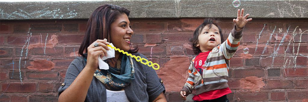 Woman playing bubbles with a toddler.